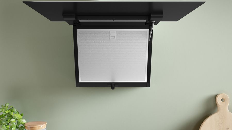 Una campana de cocina moderna, montada sobre una estufa. Es negra y está instalada en el techo.
