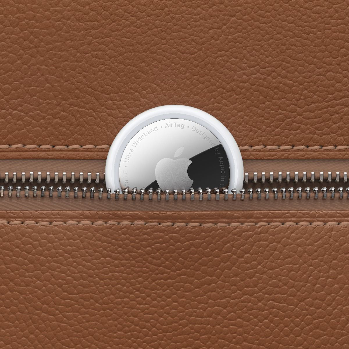 Apple AirTag eszköz részben bebújva egy barna bőr zsebbe, látható Apple logóval.