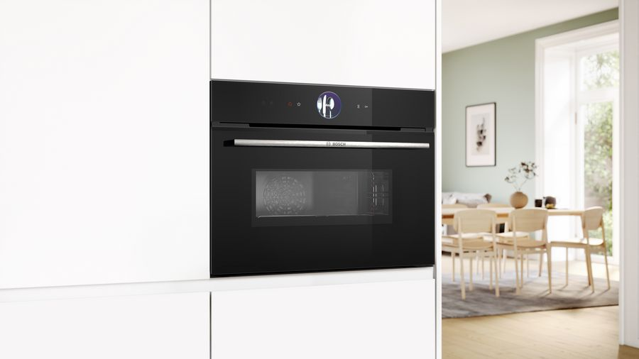 Horno negro empotrado en gabinetes blancos.