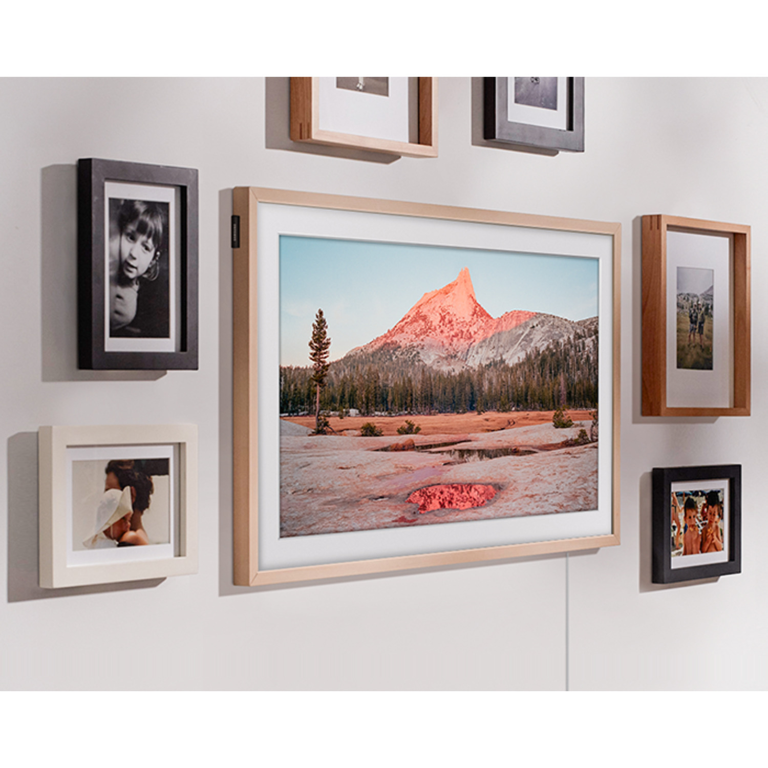 Mur avec des photos encadrées. Une grande photo encadrée présente un paysage.