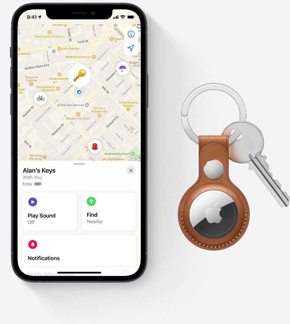 Egy telefon egy térképet jelenít meg egy kulcs ikonnal és egy AirTaggel. Egy kulcstartó kulcsokkal a közelben.