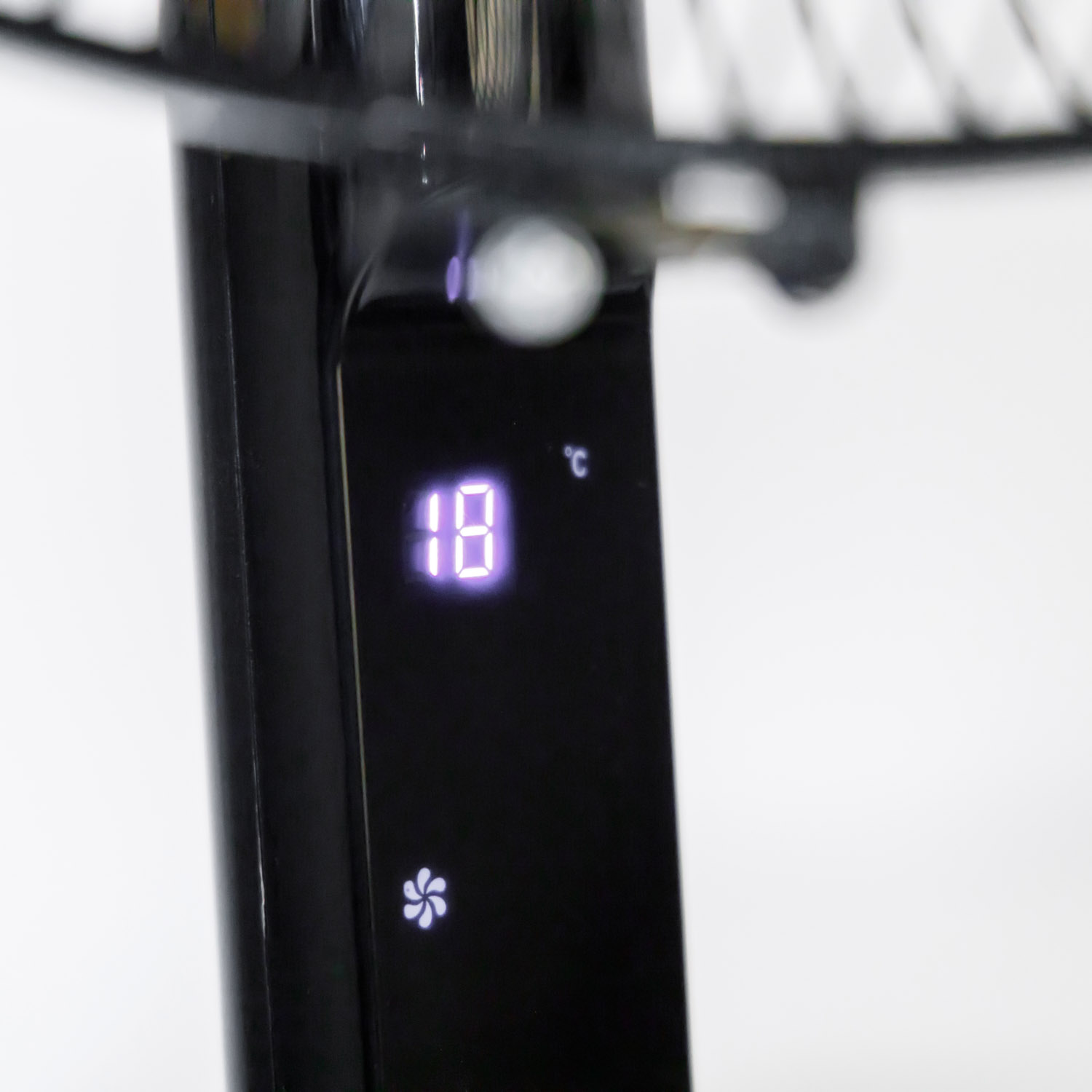 Un ventilador negro con una pantalla digital iluminada que muestra la temperatura.