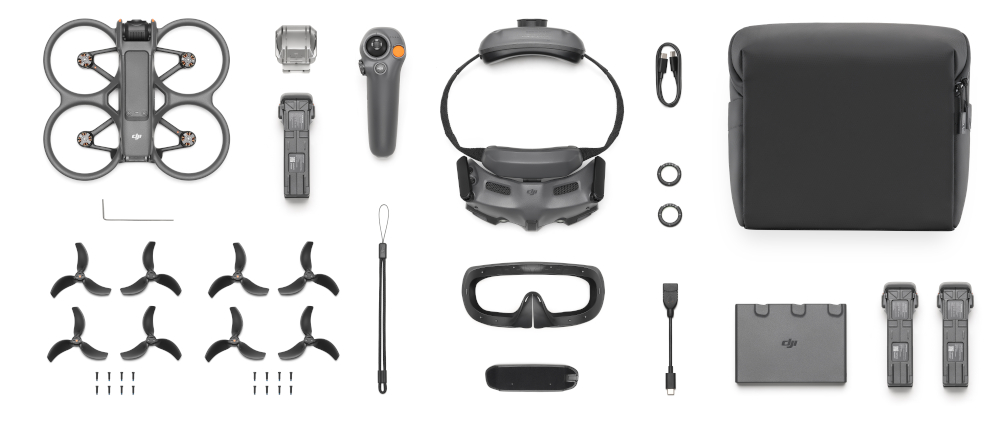Dron, kontroler, gogle i akcesoria są rozłożone na białej powierzchni. Wszystko jest szare i czarne.