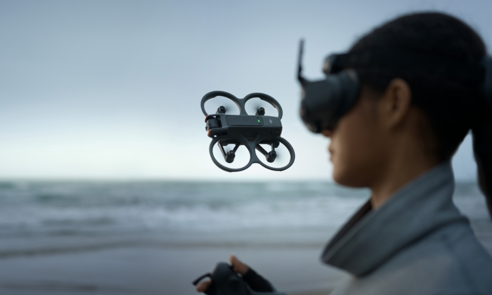 Dron latający w pobliżu osoby na plaży, noszącej gogle.