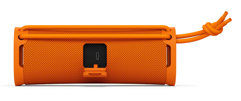 Pomarańczowy głośnik z małym portem. Po prawej stronie zawiązany pomarańczowy sznurek.