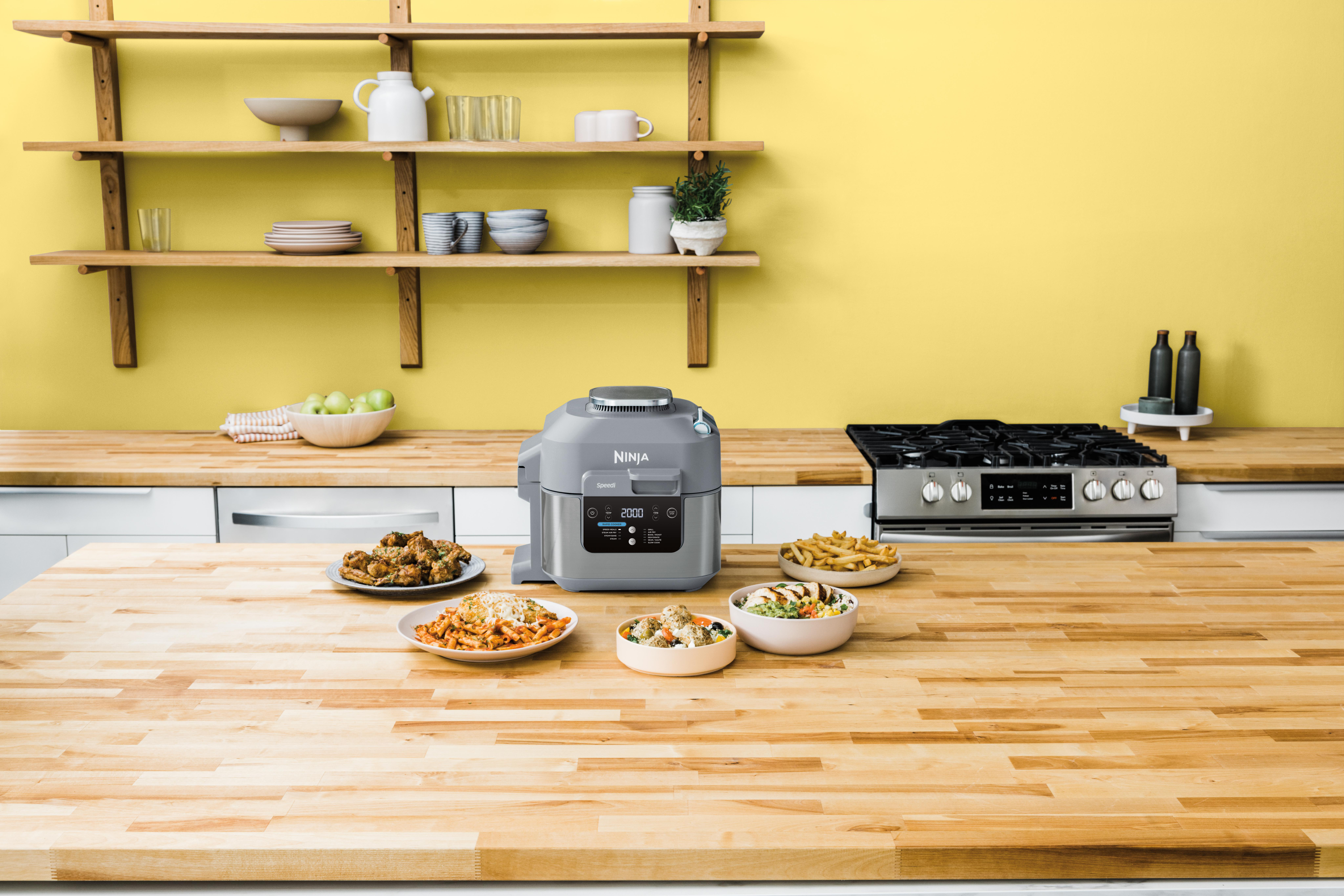 Eine Küche mit einem Ninja-Foodprozessor, Essenstellern und einem Herd auf einer Holztheke.