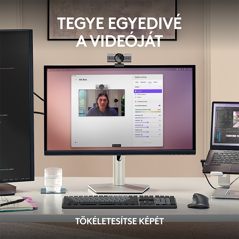 Egy asztali beállítás monitorral, webkamerával, billentyűzettel és egy pohár vízzel.
