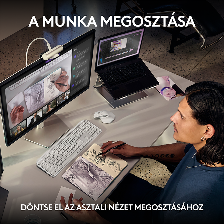 Személy vázlatot készít egy noteszre, laptop, billentyűzet és monitor mellett.