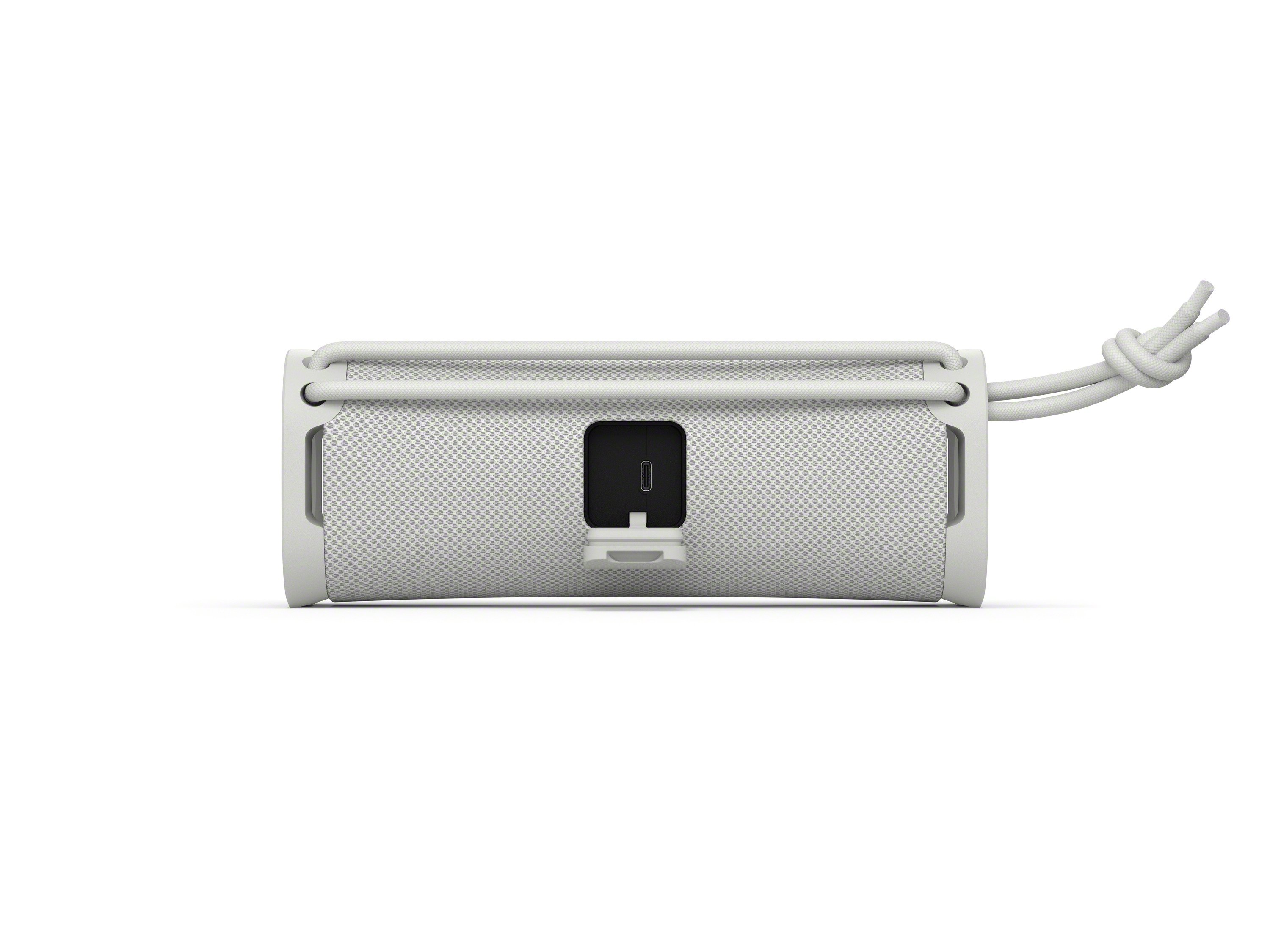 Un altavoz Sony blanco con puerto USB y una correa de transporte.