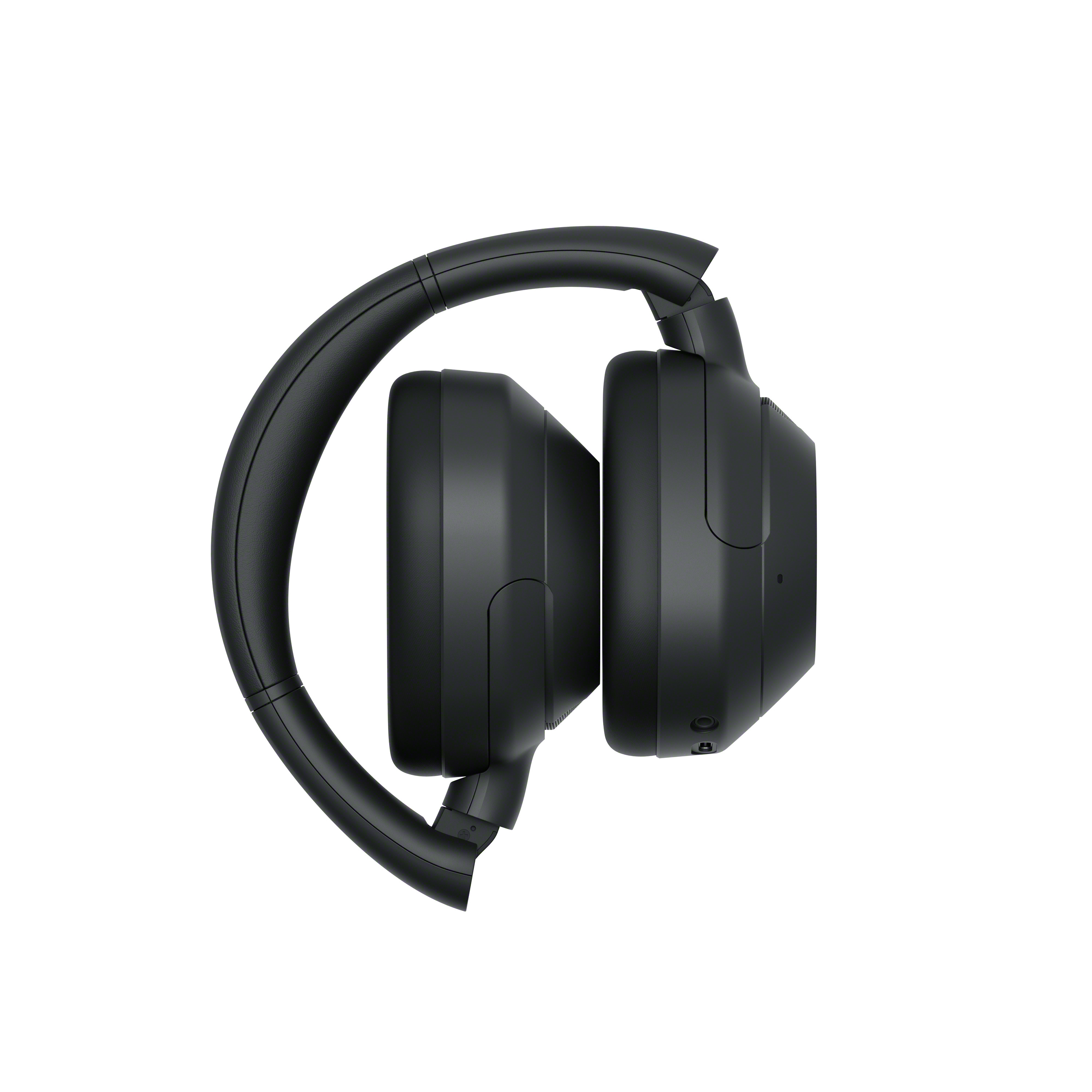 Auriculares negros plegados sobre blanco. Los auriculares están orientados uno hacia otro.