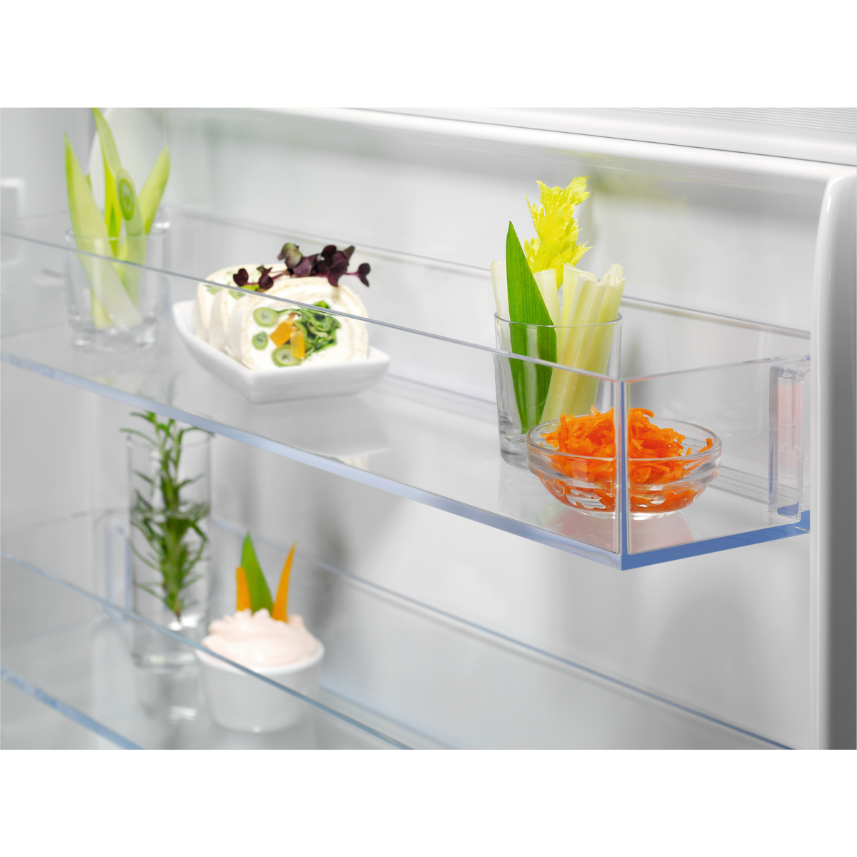 Primer plano del interior de un frigorífico con estantes de vidrio con verduras y aperitivos.