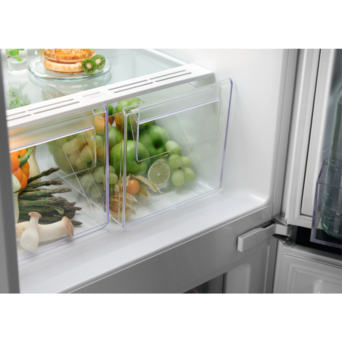 Dentro de un refrigerador con frutas, verduras y recipientes de vidrio.