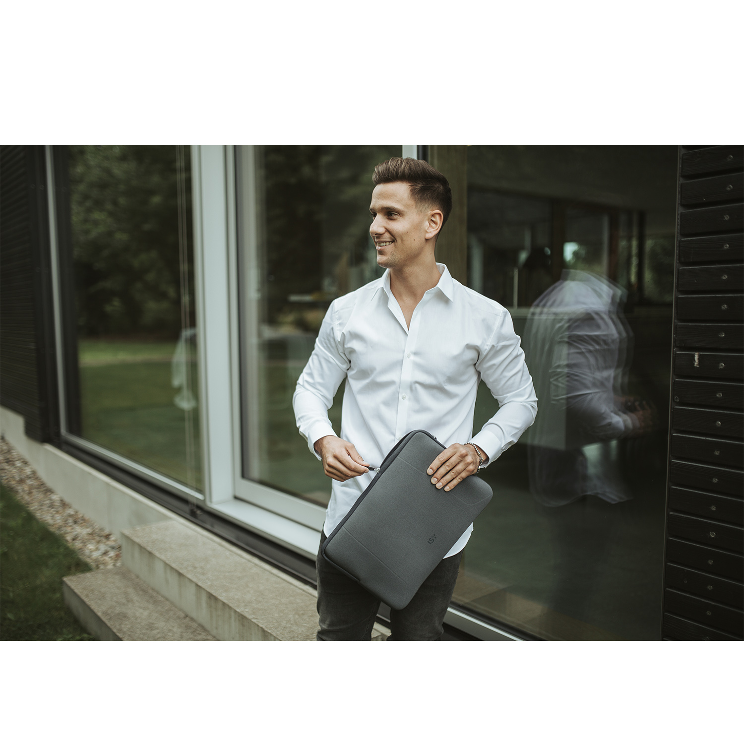 Un uomo che tiene una custodia grigia per laptop, sorridendo.