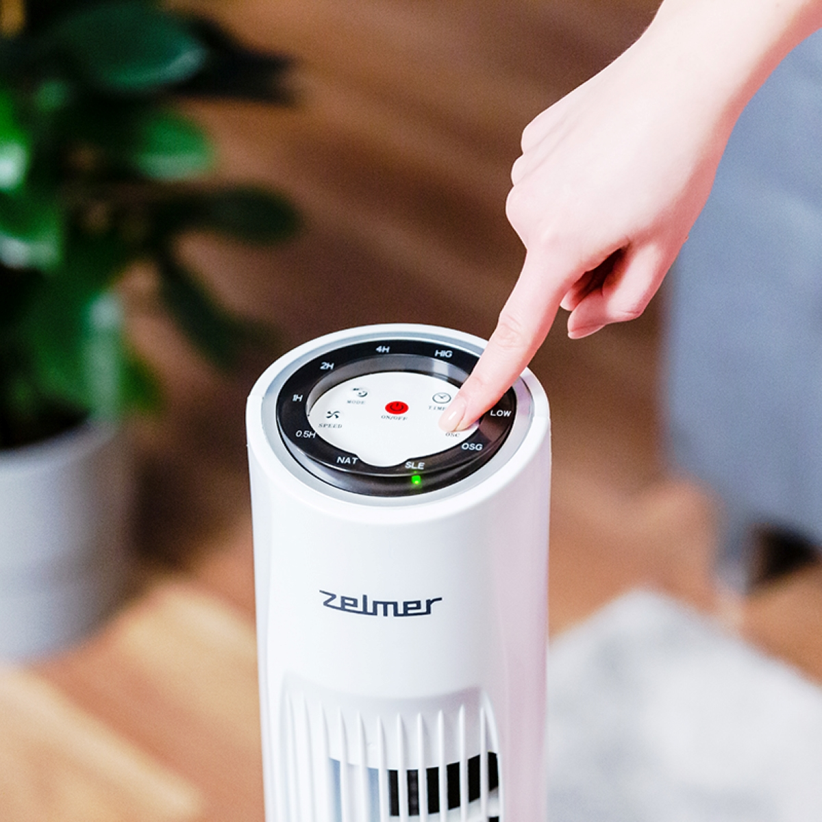 Dłoń naciskająca przycisk na białym wentylatorze, zbliżenie, wewnątrz.