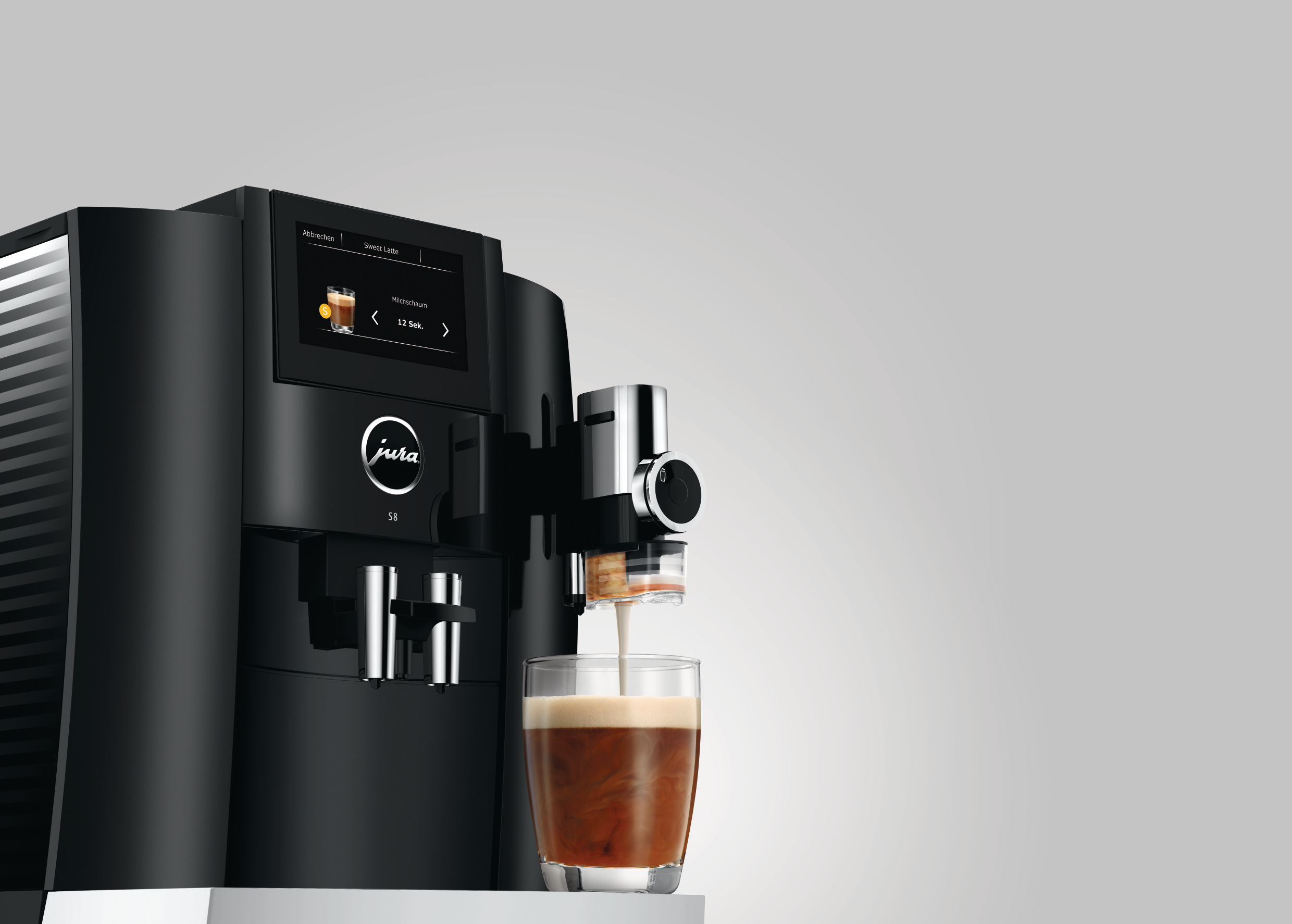 Schwarze Jura Espressomaschine mit Glas, in das Espresso gegossen wird und Schaum entsteht.