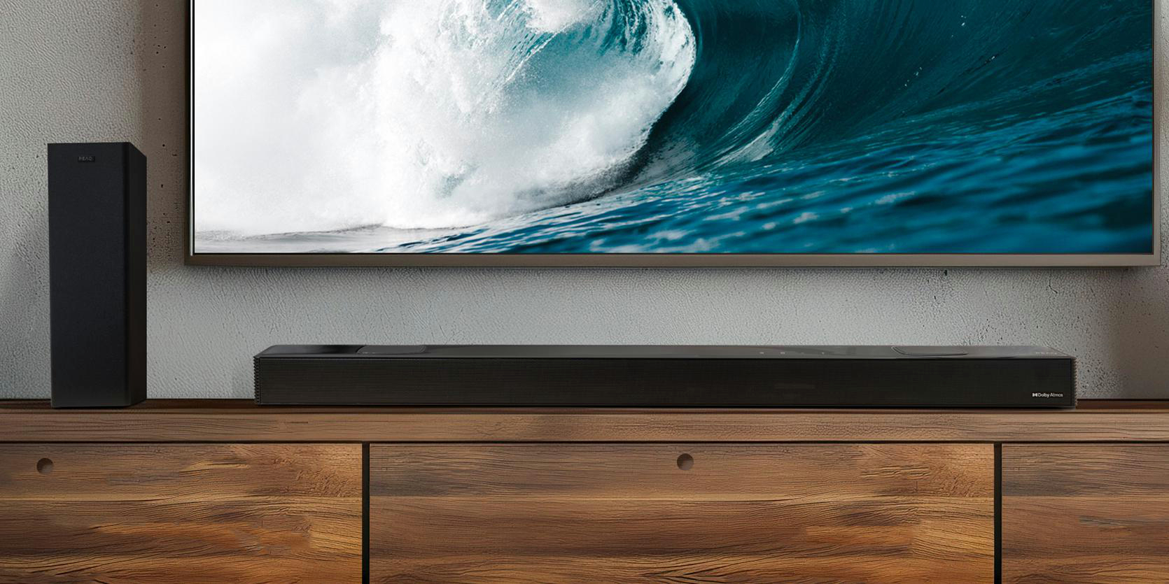 Ein Fernseher und eine Soundbar auf einem Holzschrank, mit einem großen Fenster im Hintergrund.