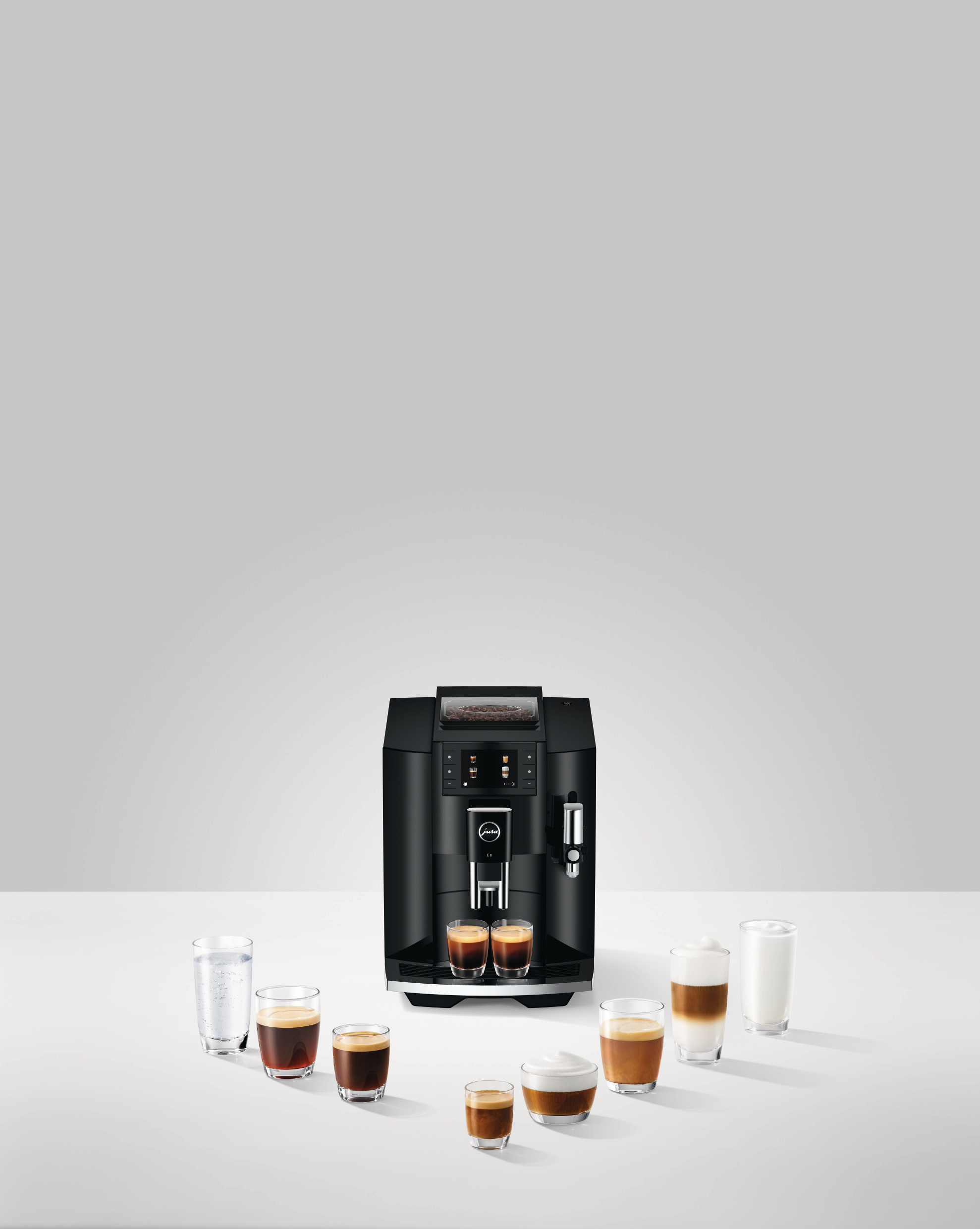 Schwarze JURA Espressomaschine mit verschiedenen Kaffeegetränken und Gläsern.