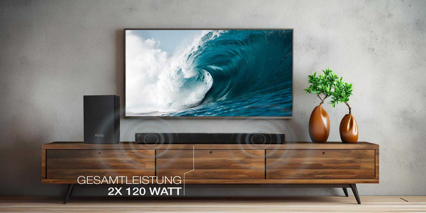 Wohnzimmer mit Fernseher, Soundbar und Dekoration. Text: Gesamtleistung 2x 120 Watt.