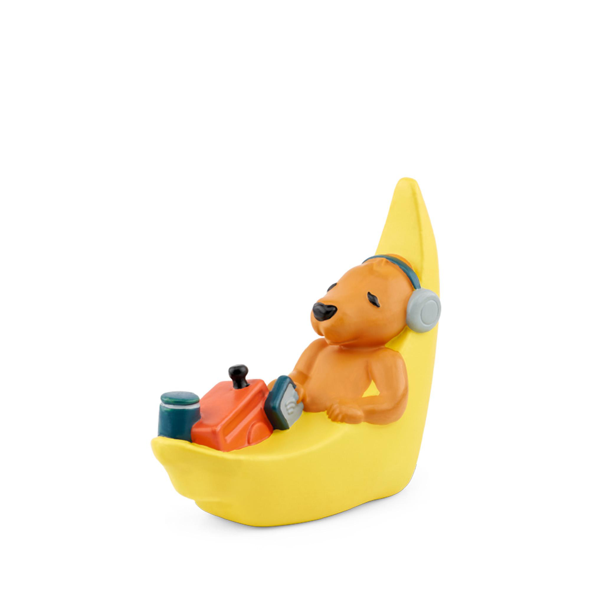 Eine Bärenfigur auf einem bananenförmigen Sitz, mit Kopfhörern und hörend.