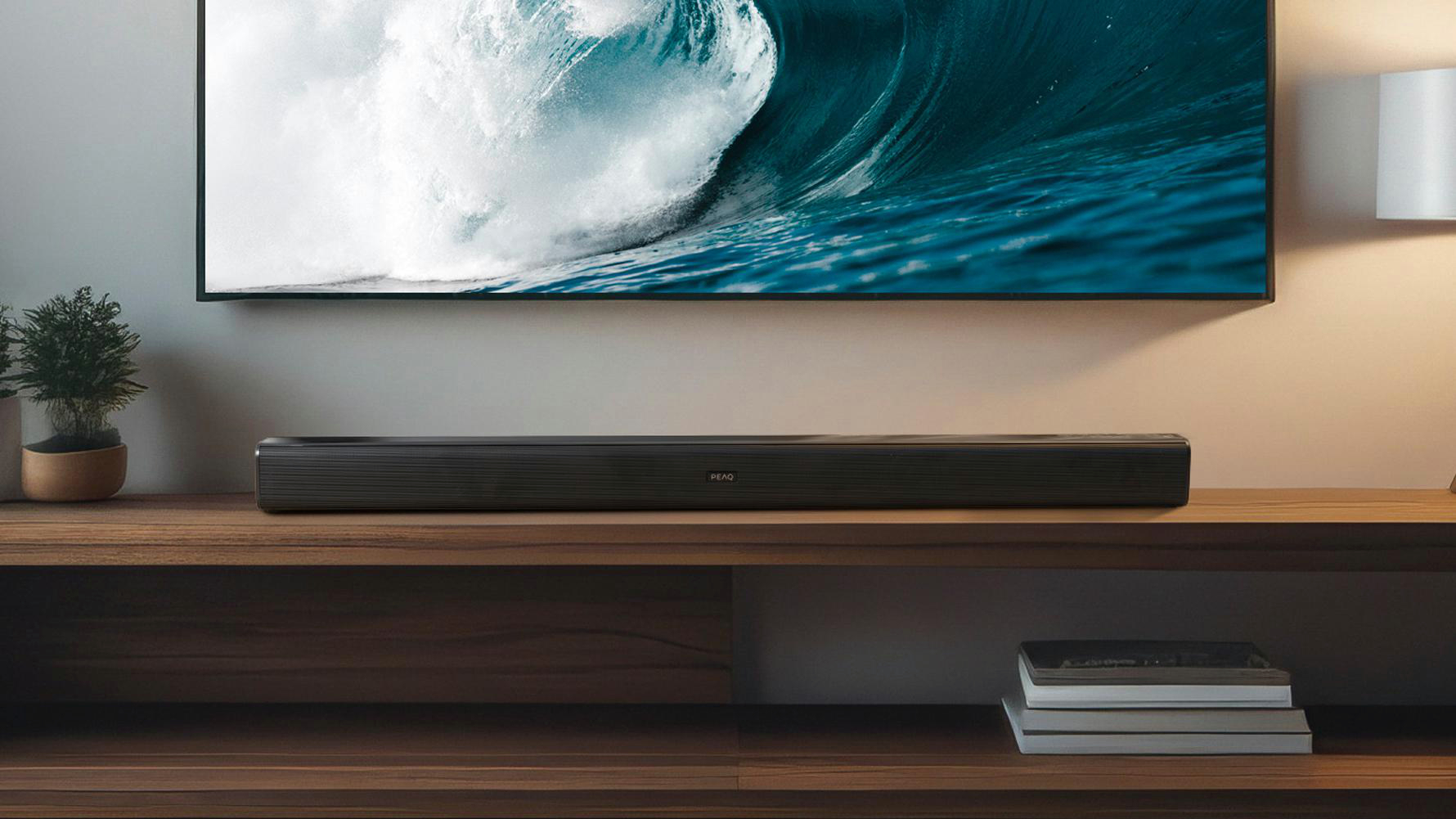 Eine lange, schwarze Soundbar befindet sich unter einem großen Fernseher, der eine Welle zeigt.
