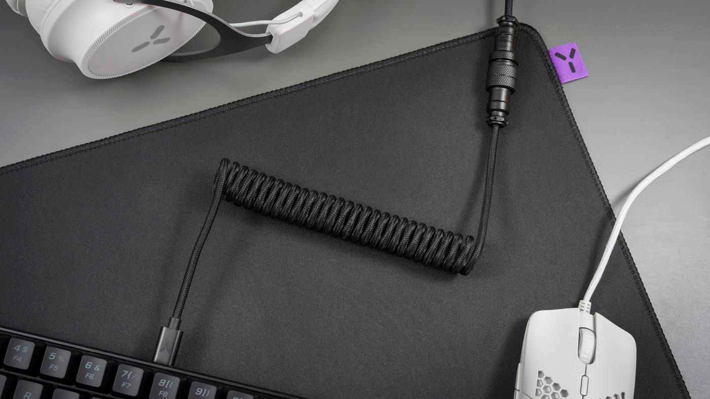 Schwarzes Mauspad mit Spiralkabel und weißer Gaming-Maus, Draufsicht.