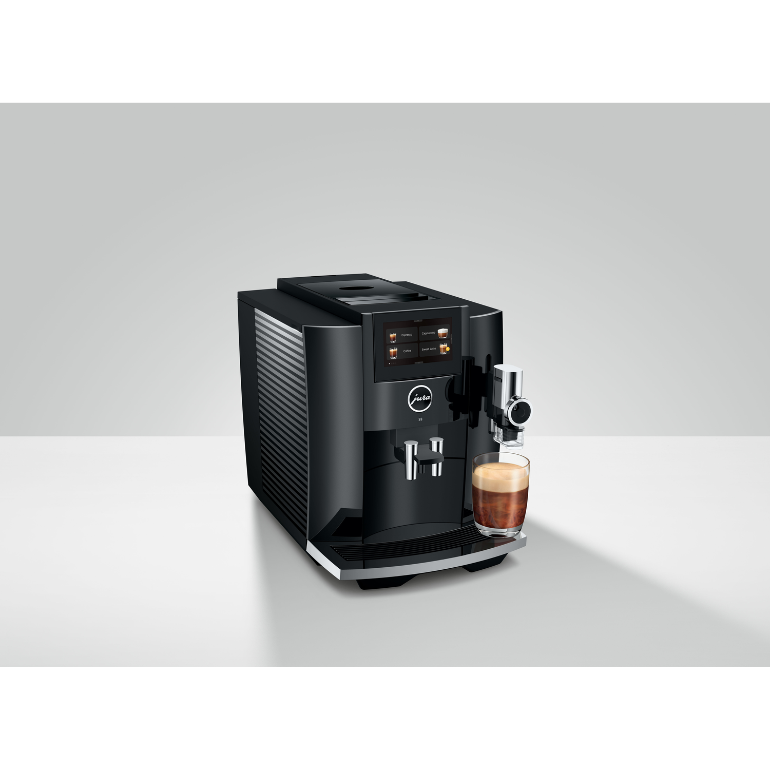 A black coffee machine with a glass of coffee being poured. It's on a white surface.