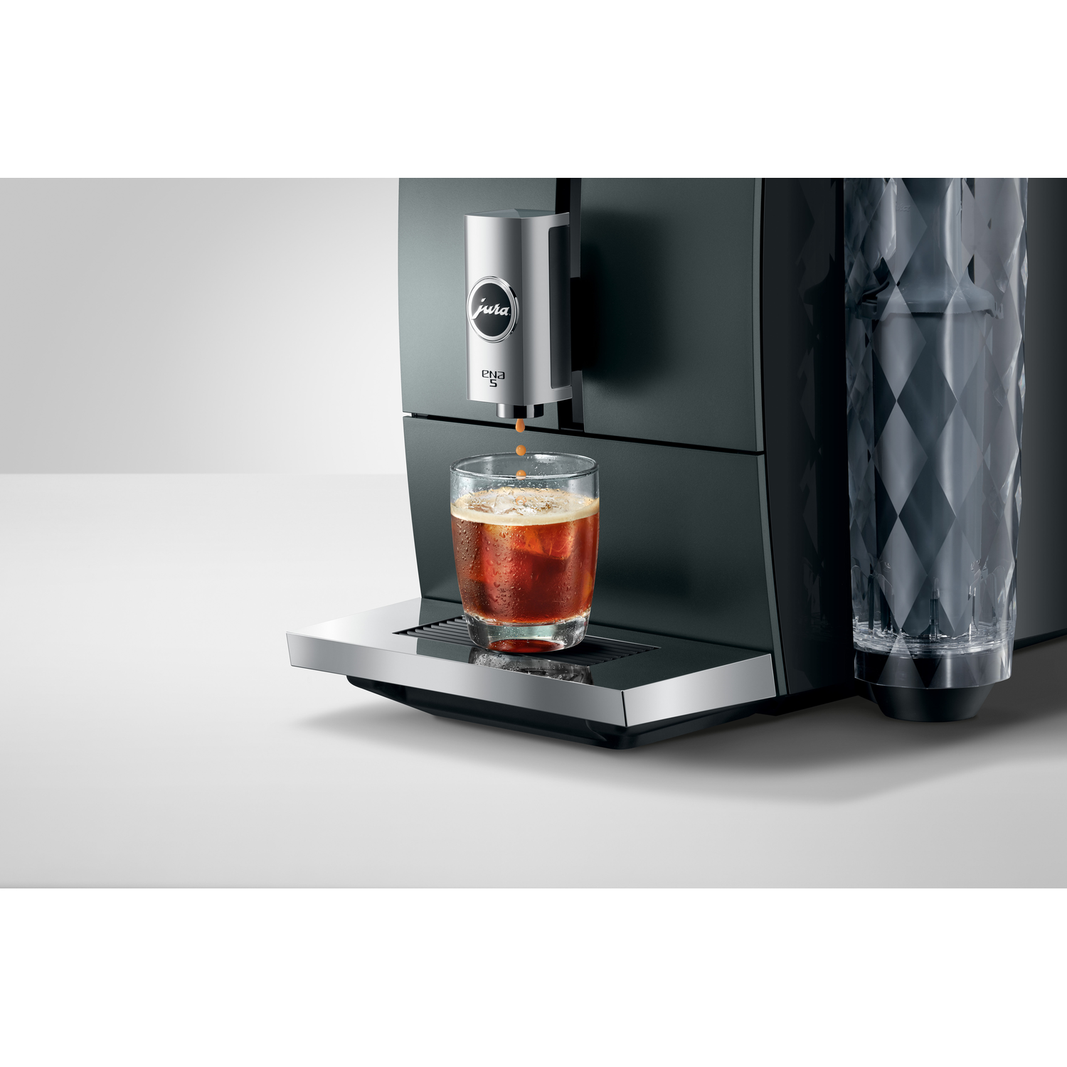 Espresso machine dispensing coffee into a glass with ice, on a white surface.