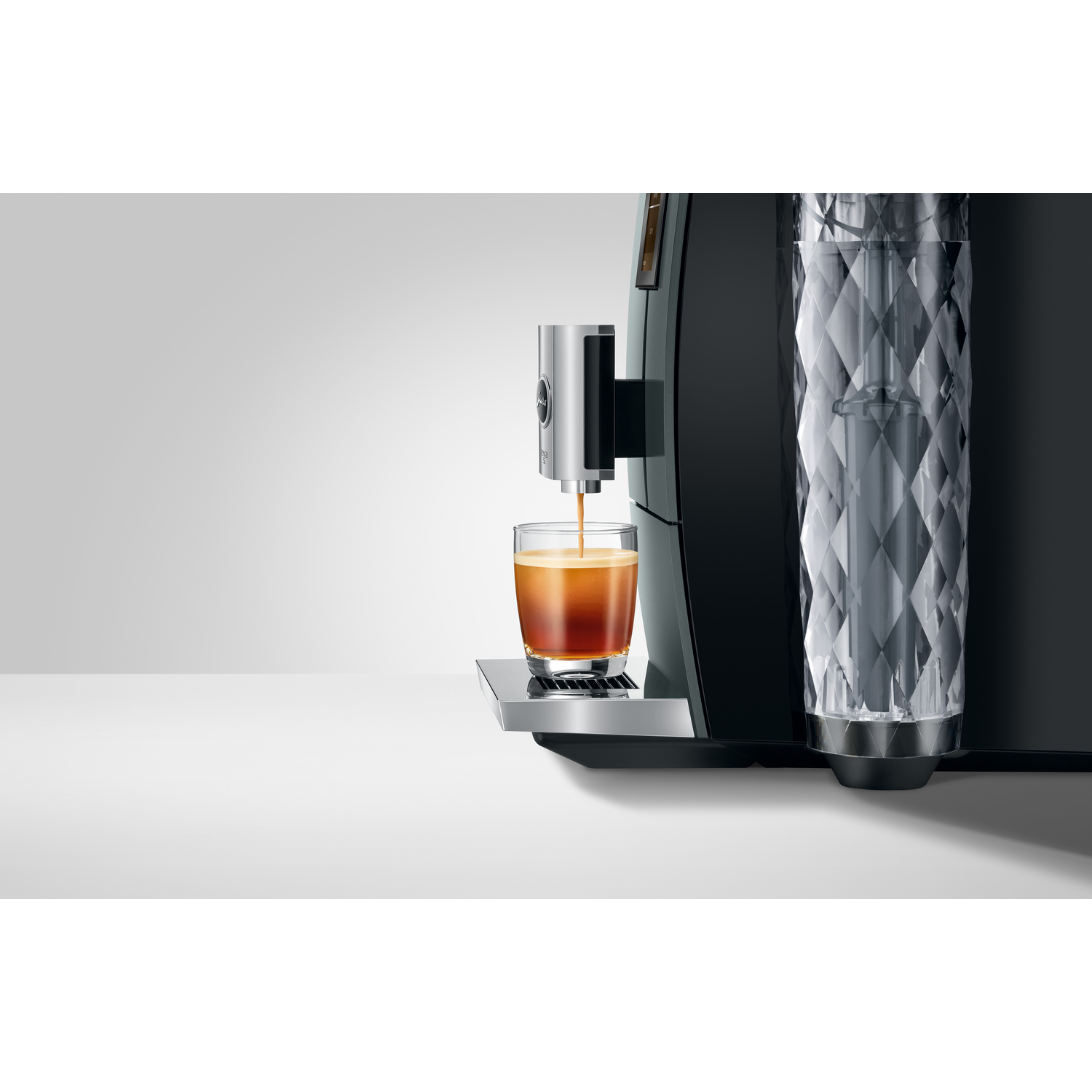 Espresso machine pouring coffee into a glass. Machine has a water container on the right.