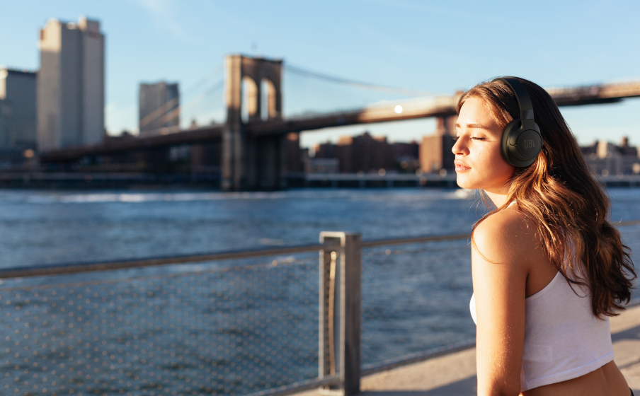 Nő fejhallgatóval, a háttérben a Brooklyn híd.