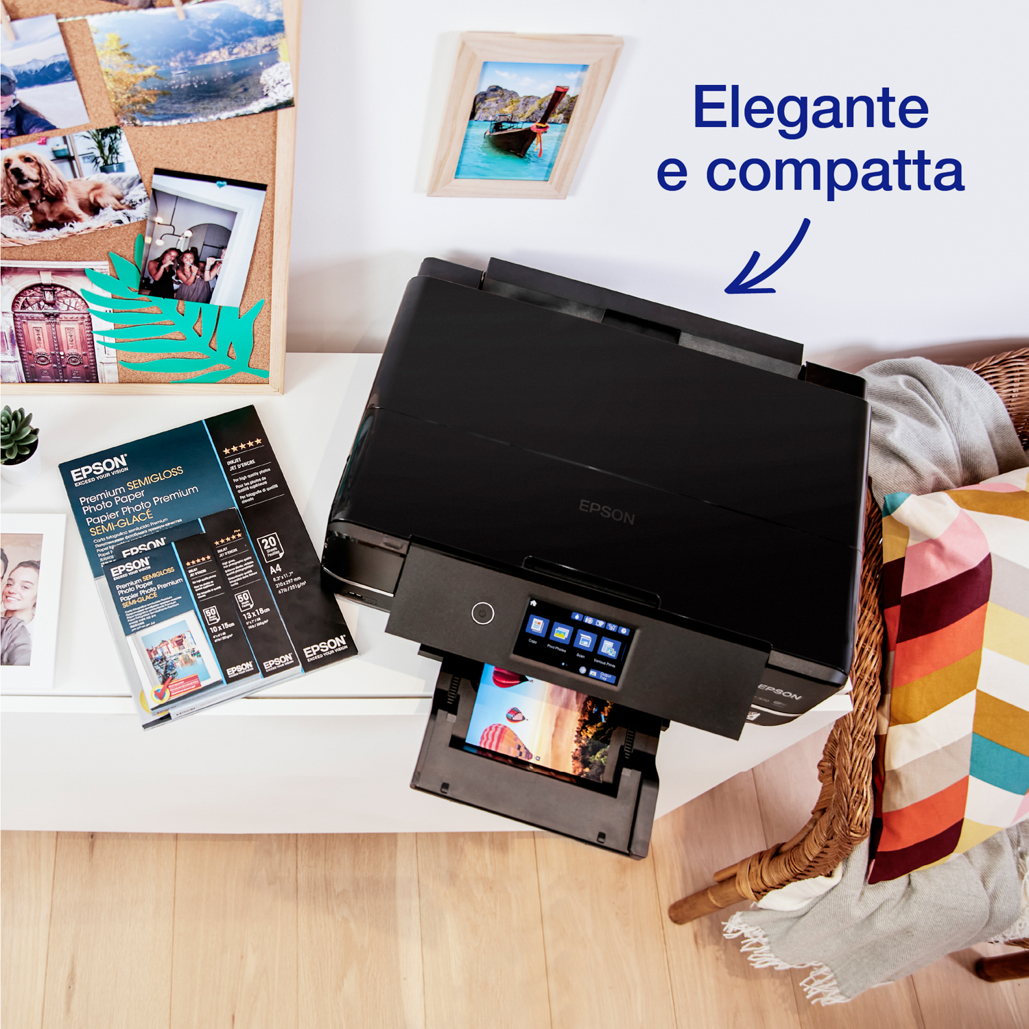 Stampante Epson nera che stampa un'immagine, con vari oggetti su un tavolo bianco e un cestino di vimini.