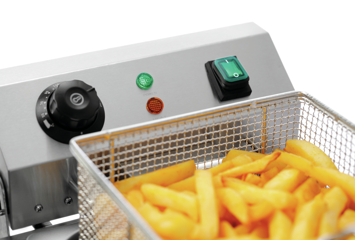 Nahaufnahme einer Fritteuse mit Pommes Frites in einem Metallkorb. Sie hat einen Einschaltknopf, einen Temperaturregler und Kontrollleuchten.