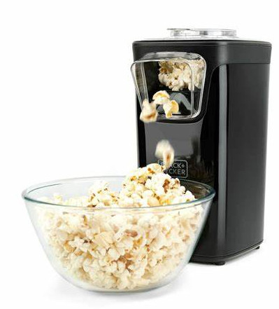 Czarna maszyna do popcornu dozująca popcorn do przezroczystej szklanej miski.