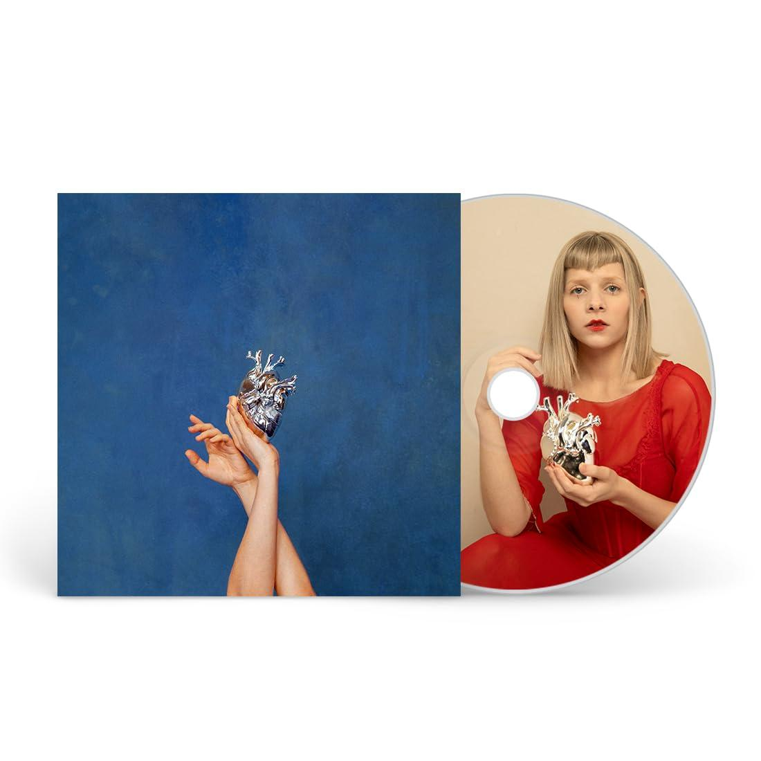 Albumcover: Eine Frau in Rot mit einem herzförmigen Objekt.
