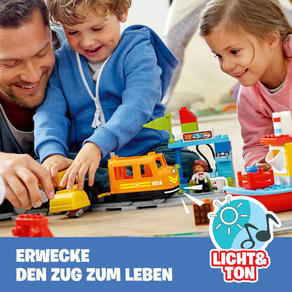 Kinder spielen mit einer Eisenbahn.
