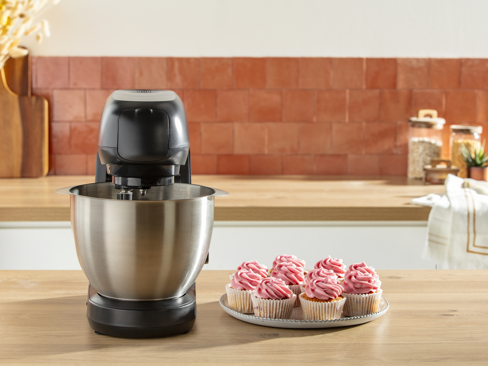 Egy fekete mixer táljában muffinokkal egy fa pulton. Vörös csempés fal.