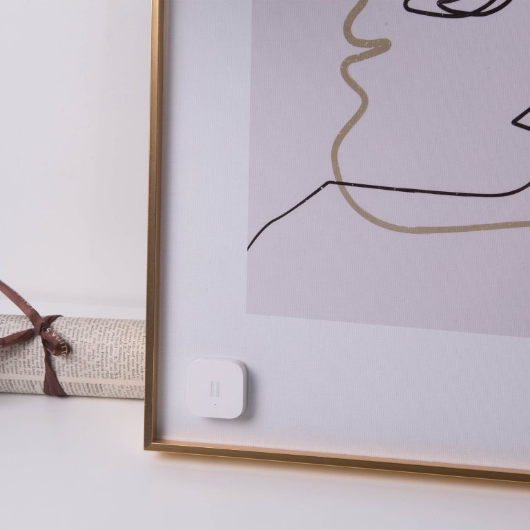 Un'opera d'arte moderna con un sensore bianco attaccato a una cornice dorata.