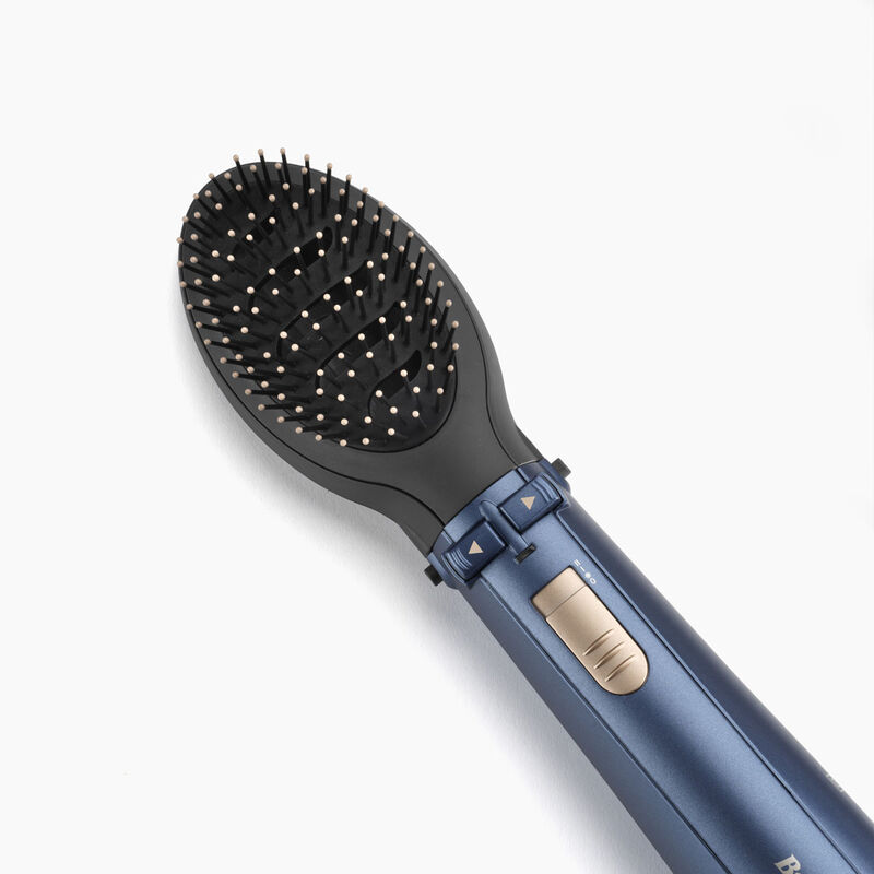 Primer plano de un cepillo para peinar el cabello azul y negro con un botón dorado.