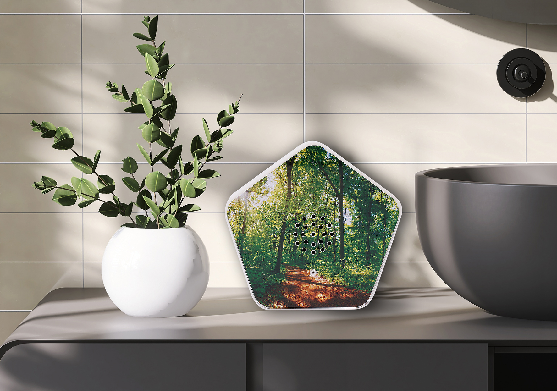 Weiße Vase mit grüner Pflanze, ein Waldbild auf einem Lautsprecher und ein schwarzes Waschbecken.