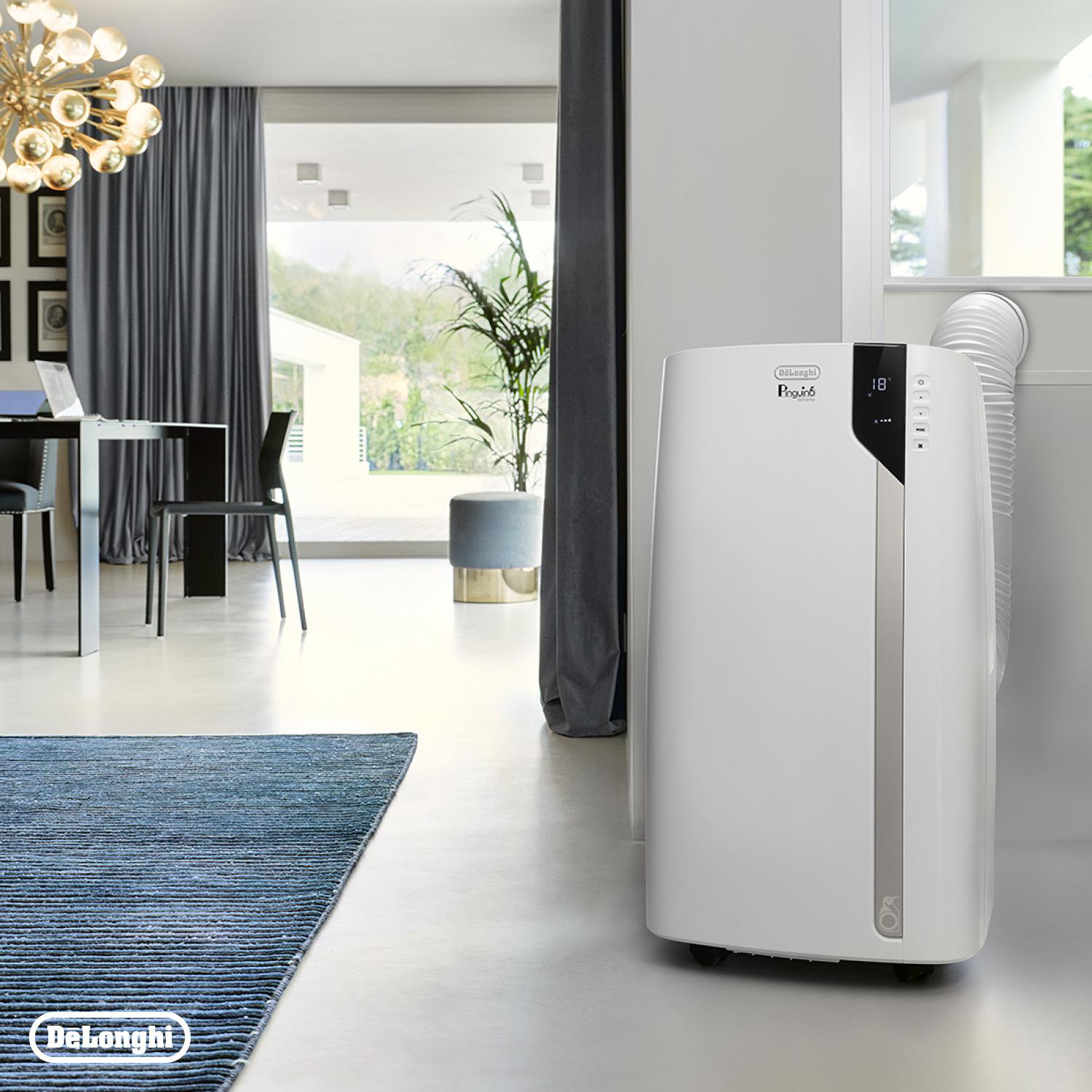 Weißer DeLonghi Klimaanlage in einem Raum, offene Tür nach draußen, blauer Teppich.