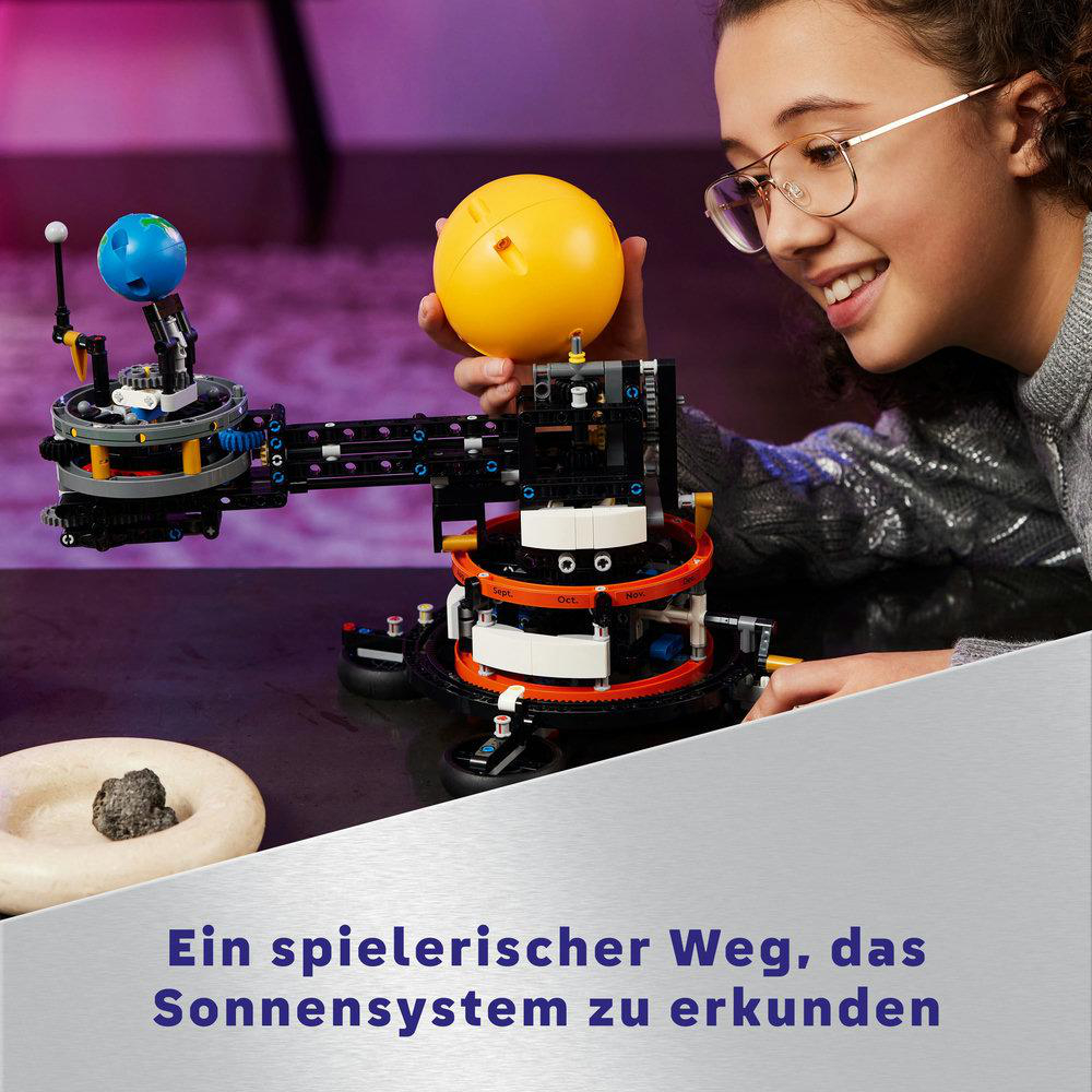 Ein Mädchen interagiert mit einem LEGO-Sonnensystemmodell, lächelt und trägt eine Brille.