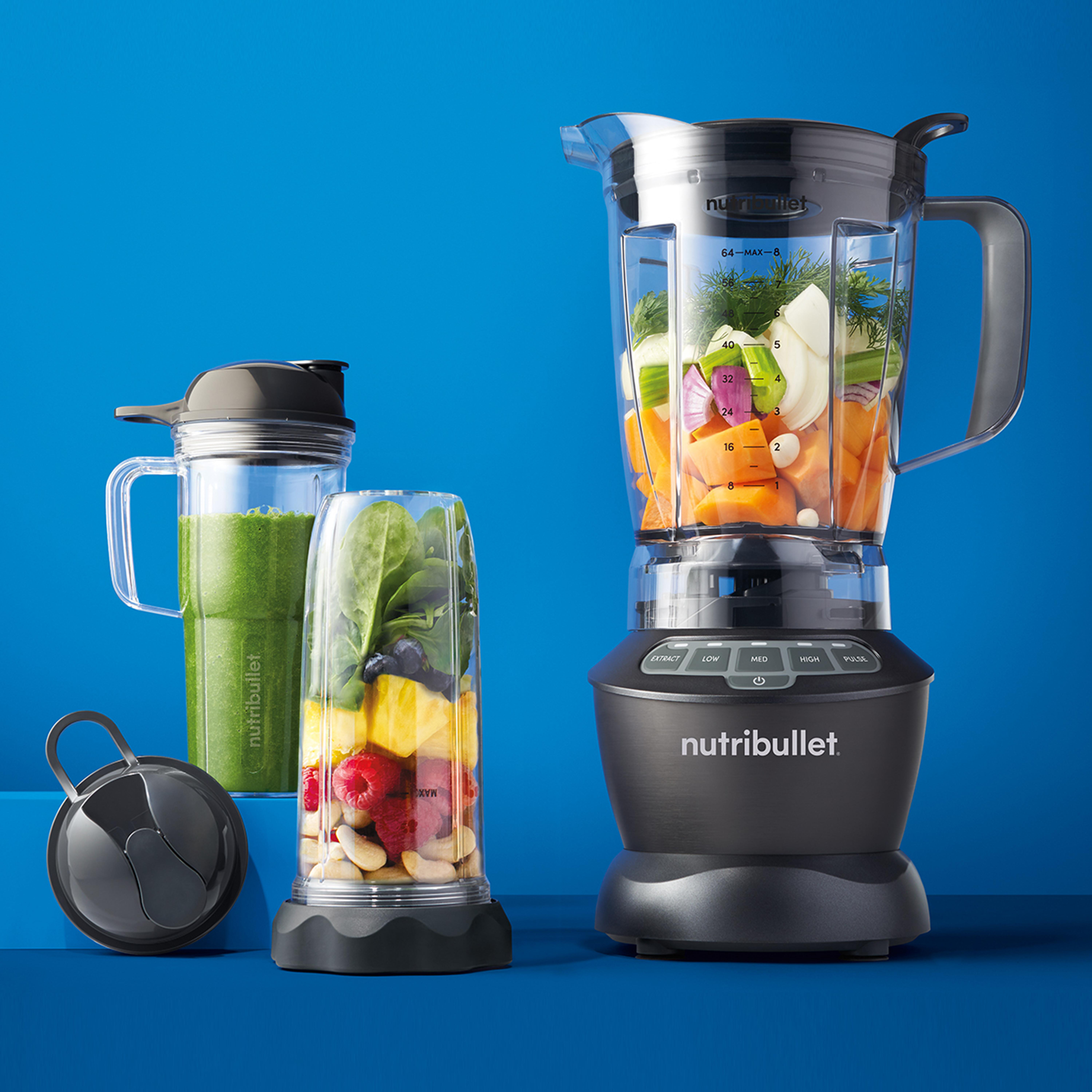 Ein Nutribullet-Mixer mit Zutaten und einem grünen Smoothie auf blauem Hintergrund.