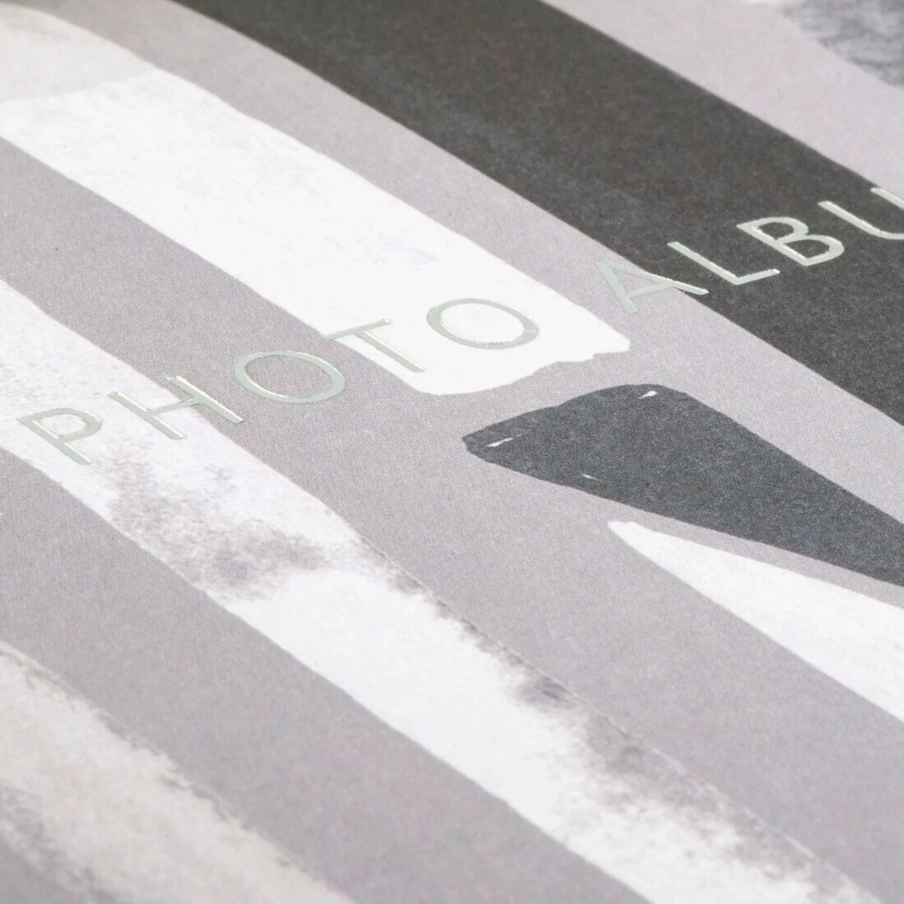 Zbliżenie albumu fotograficznego z szaro-białym wzorem w paski. Widoczny jest tekst "PHOTO ALBUM".