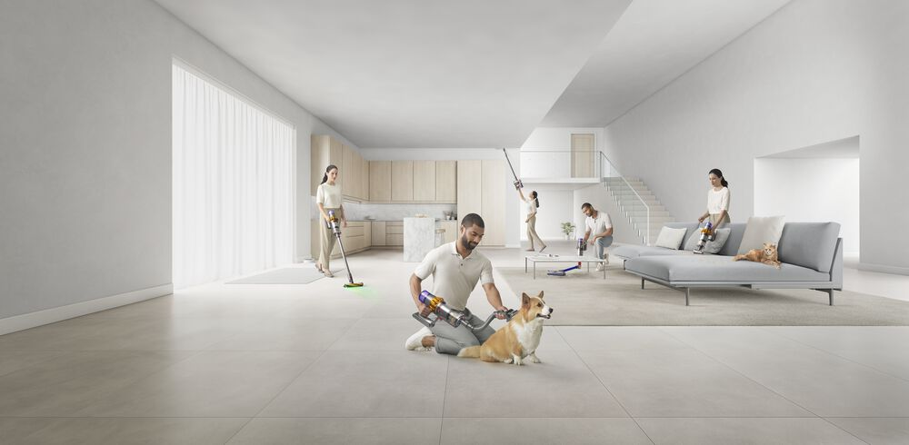Personas usando aspiradoras Dyson en un hogar moderno. Uno aspira a un perro. Blanco y madera clara.
