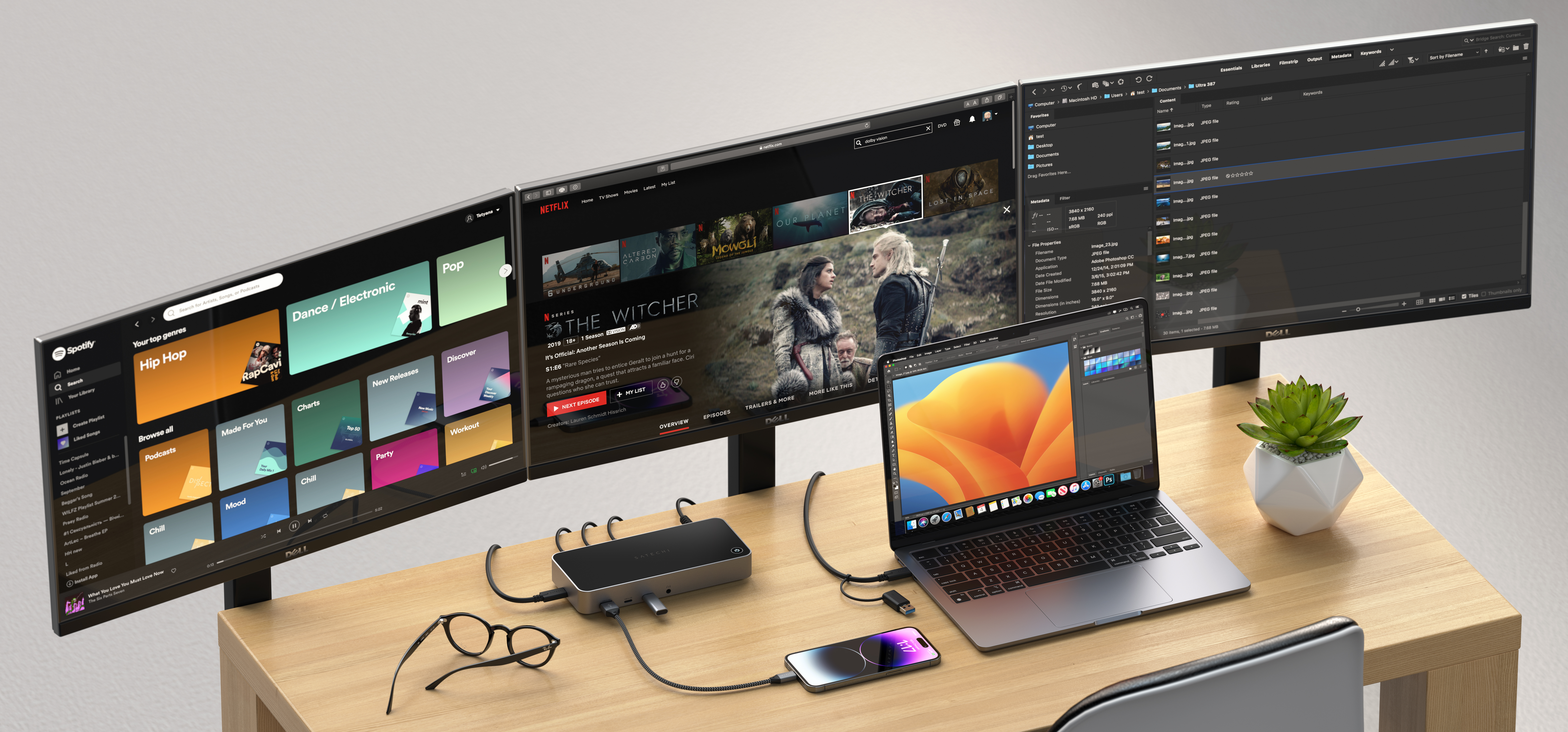 Ein Schreibtisch-Setup mit drei Monitoren, einem Laptop, einer Dockingstation und einem Telefon.