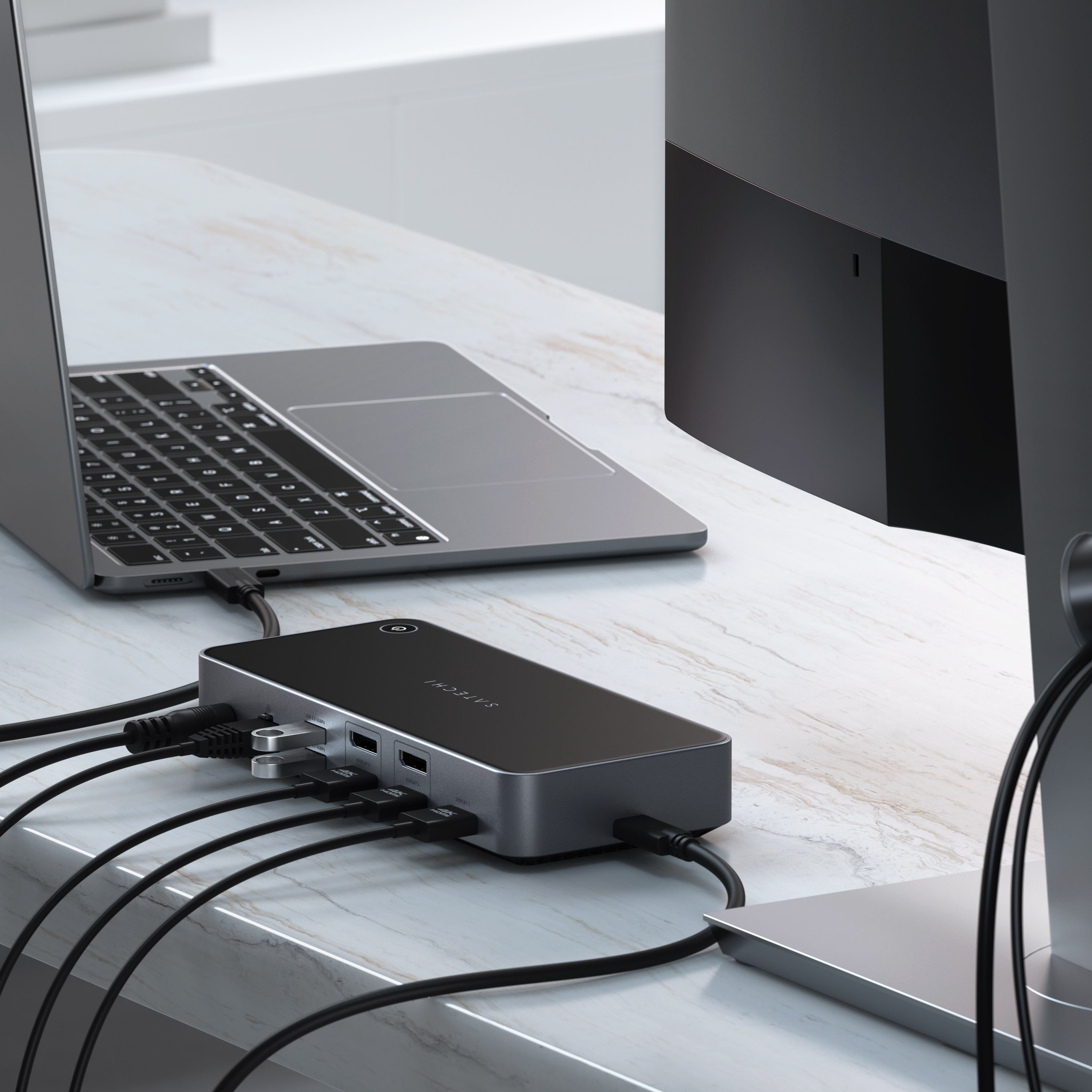 Schwarzer Hub mit mehreren Anschlüssen, die mit Laptop und Monitor verbunden sind.