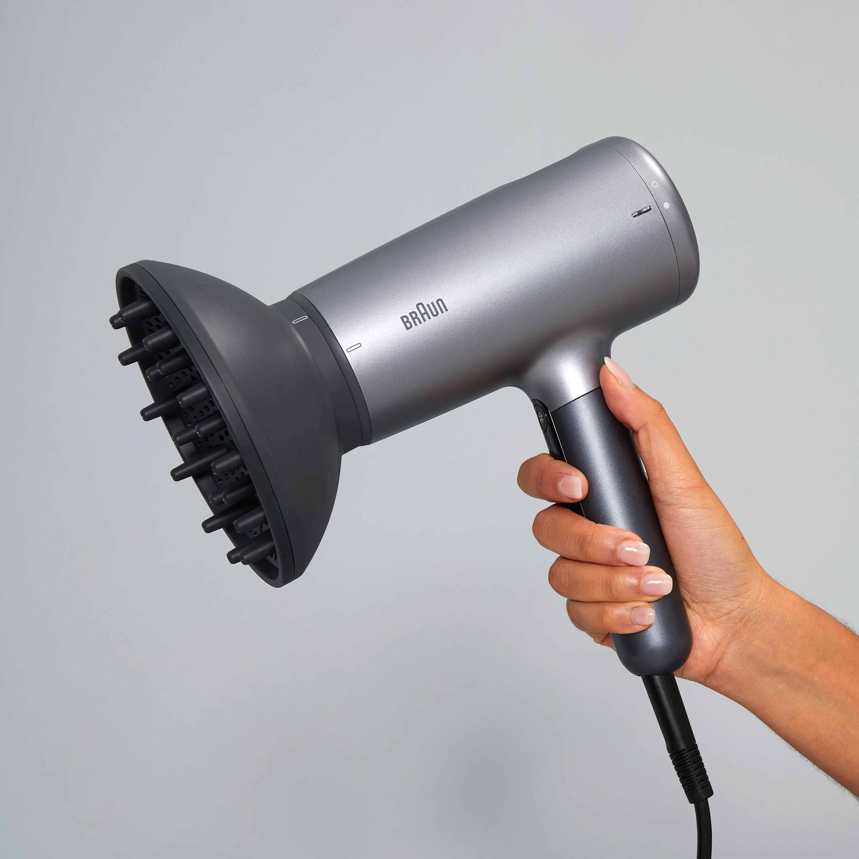 Eine Person hält einen grauen Braun-Haartrockner.