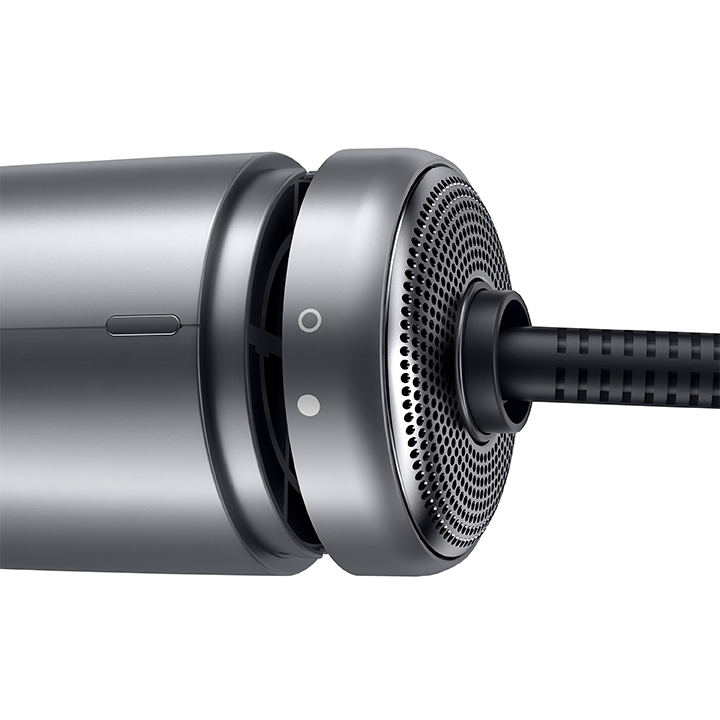 Nahaufnahme eines silbernen Geräts mit perforierter Metalloberfläche, mit zwei Knöpfen und einem Kabel.