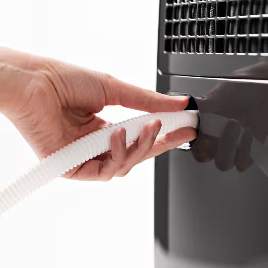 Una mano che collega un tubo corrugato bianco a un apparecchio grigio scuro su sfondo bianco.