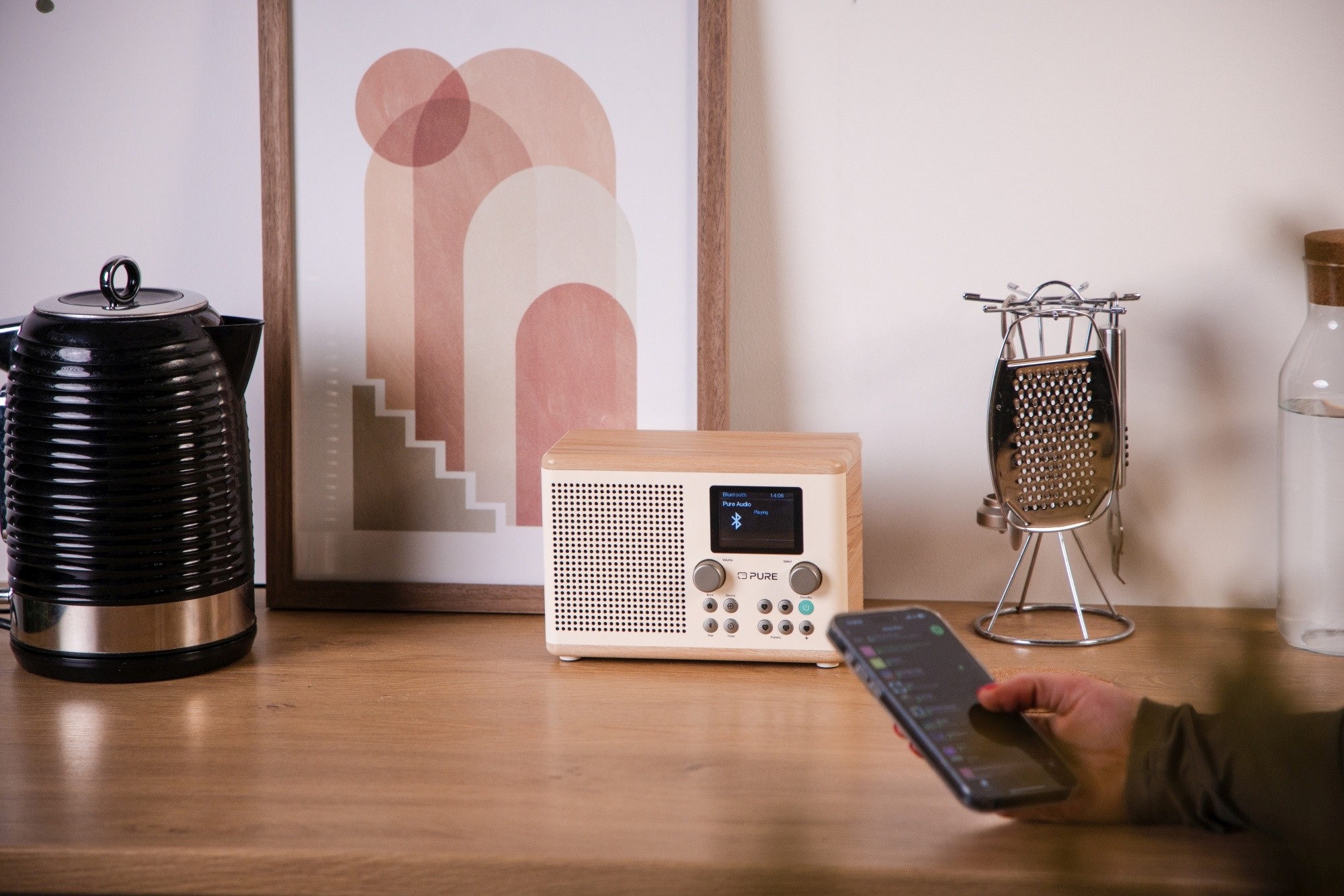 Radio mit Holzoberfläche, Telefon und Wasserkocher auf Holzoberfläche. Kunstwerk im HG.