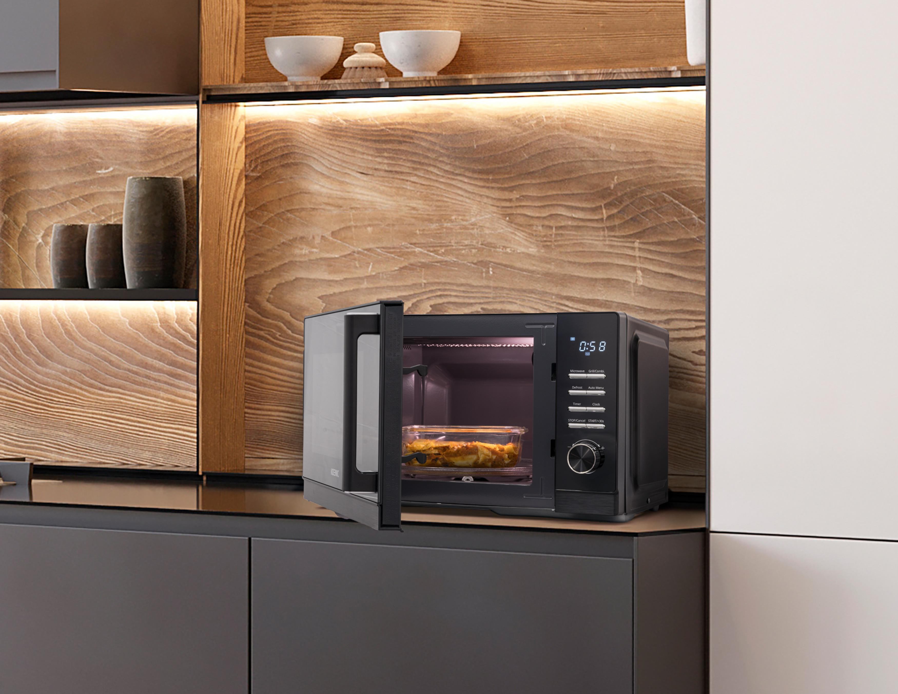 Ein Mikrowellenherd, geöffnet, mit Essen darin, auf einer Theke in einer Küche.